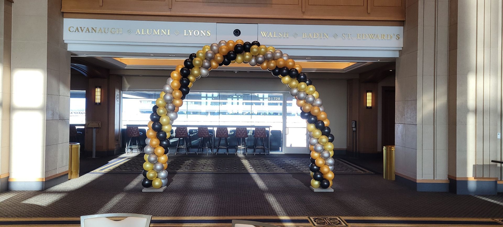 There is a large arch made of balloons in the middle of a room.