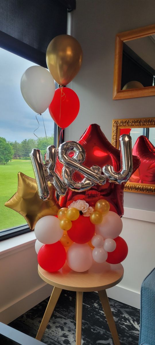 A table topped with red , white , and gold balloons. Balloon Marquee