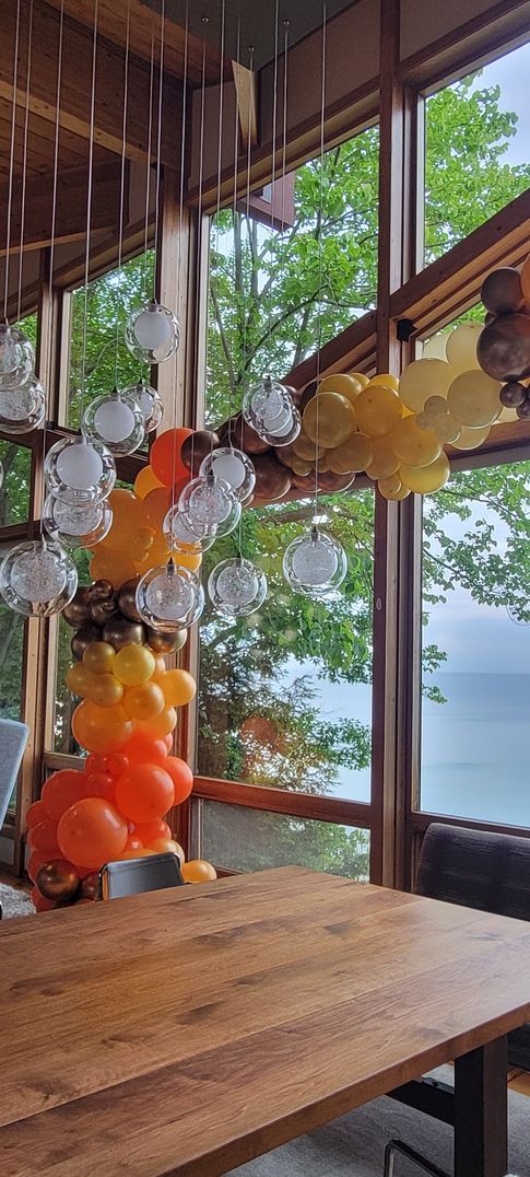A room with a wooden table and balloons hanging from the ceiling.
