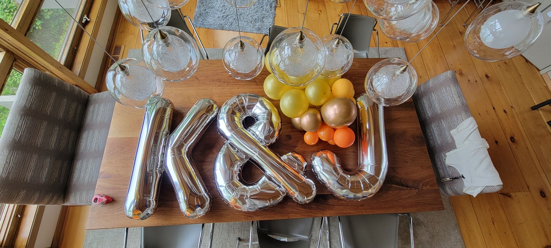 A wooden table with balloons in the shape of the letter k and u on it.