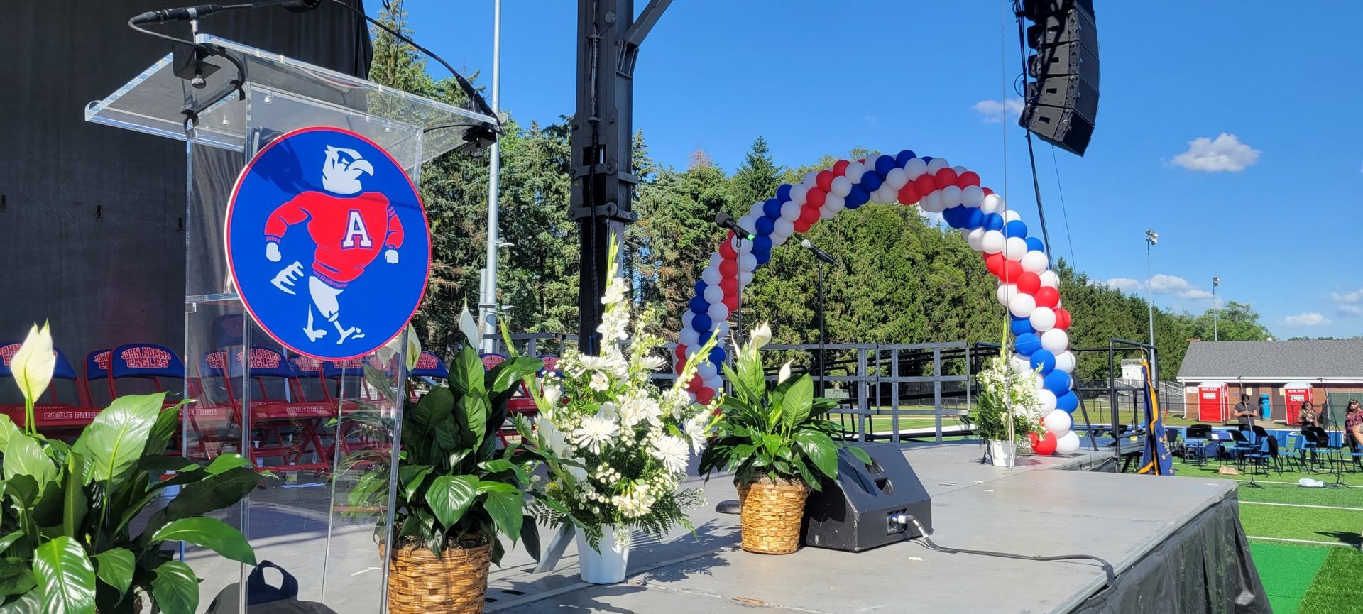 A stage with a podium and graduation balloon arch on it.