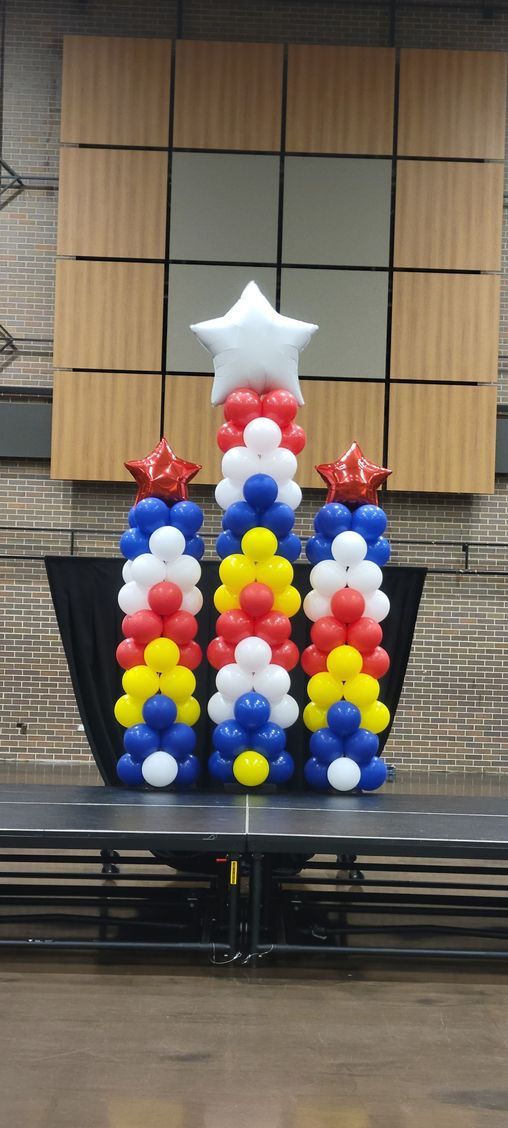Balloon columns in a chevron pattern with star toppers on a stage at Century Center.