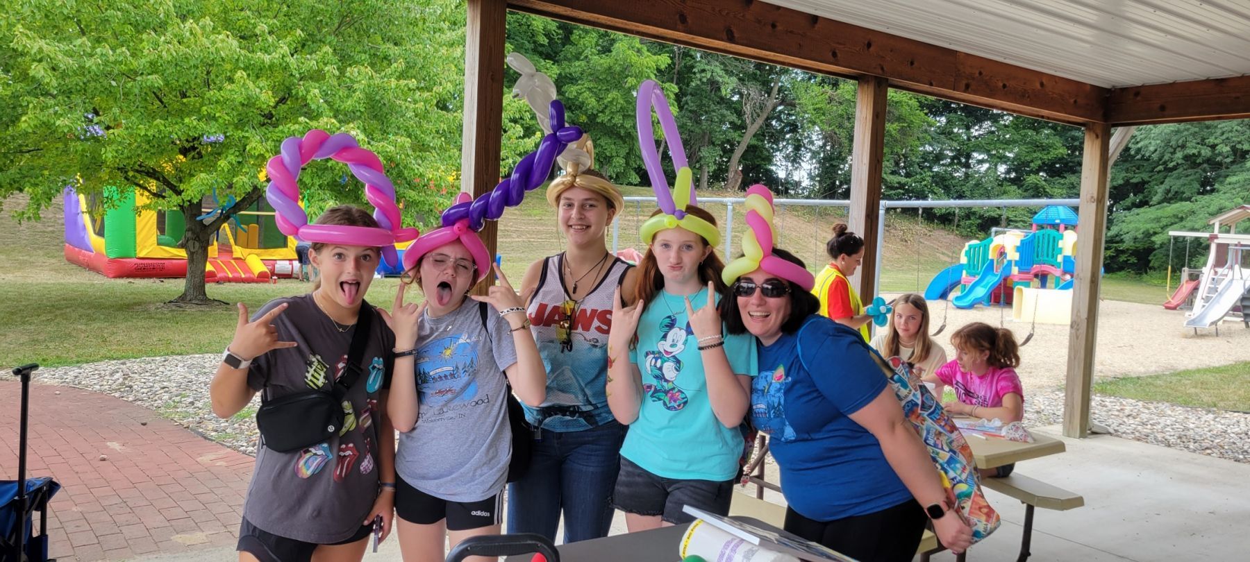 A group of people wearing balloon hats are posing for a picture in a park.