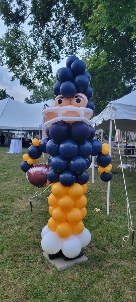 A statue of a football player made out of balloons in a field.