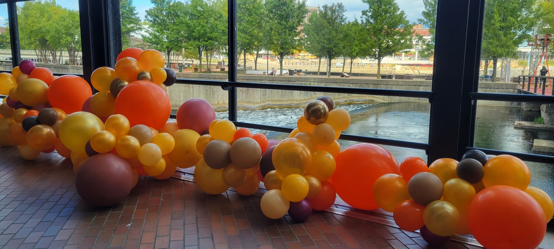 A bunch of balloons are sitting on the floor in front of a window.