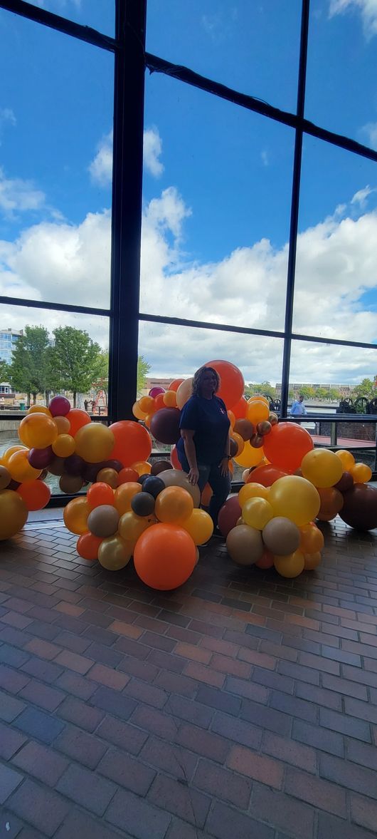 A bunch of balloons are sitting on the floor in front of a window.