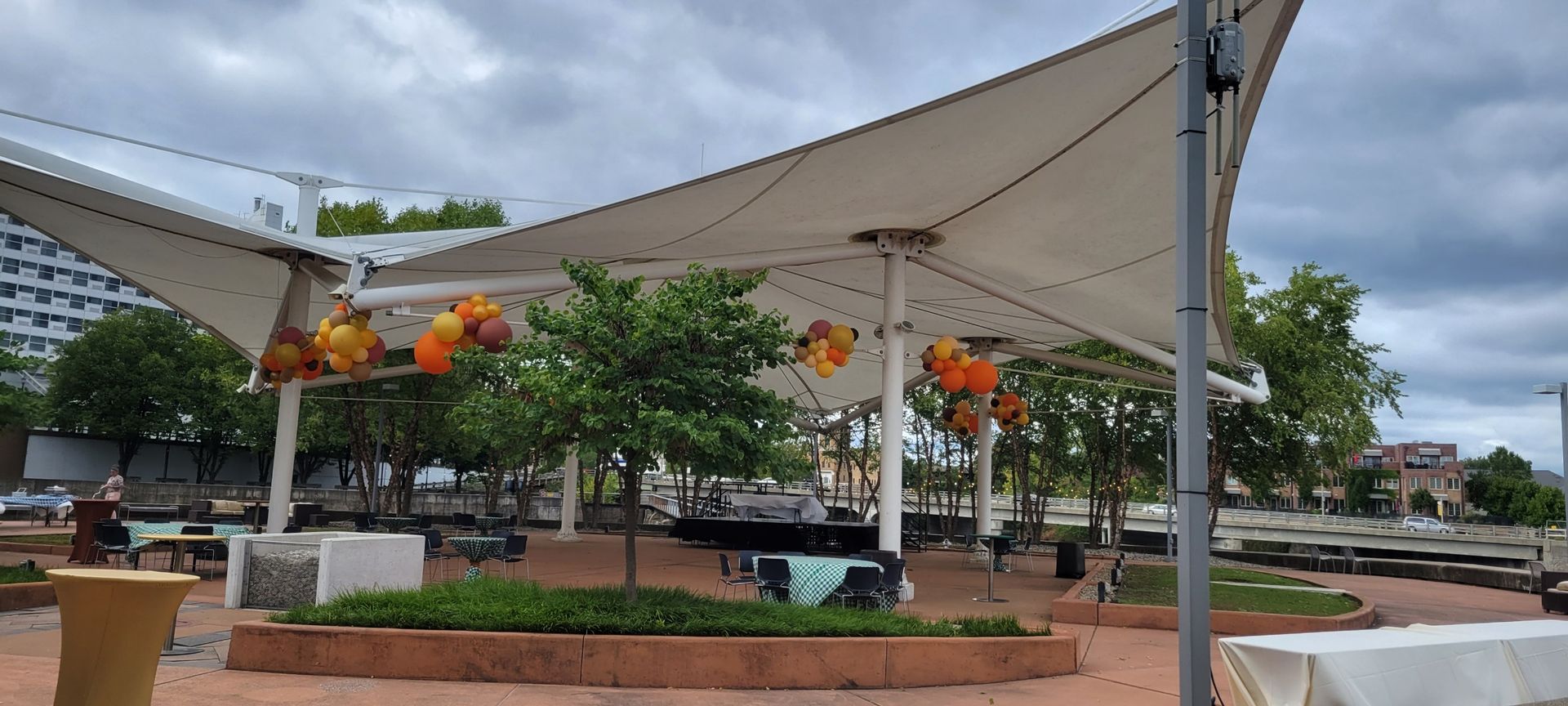 A large white umbrella is sitting in the middle of a park.