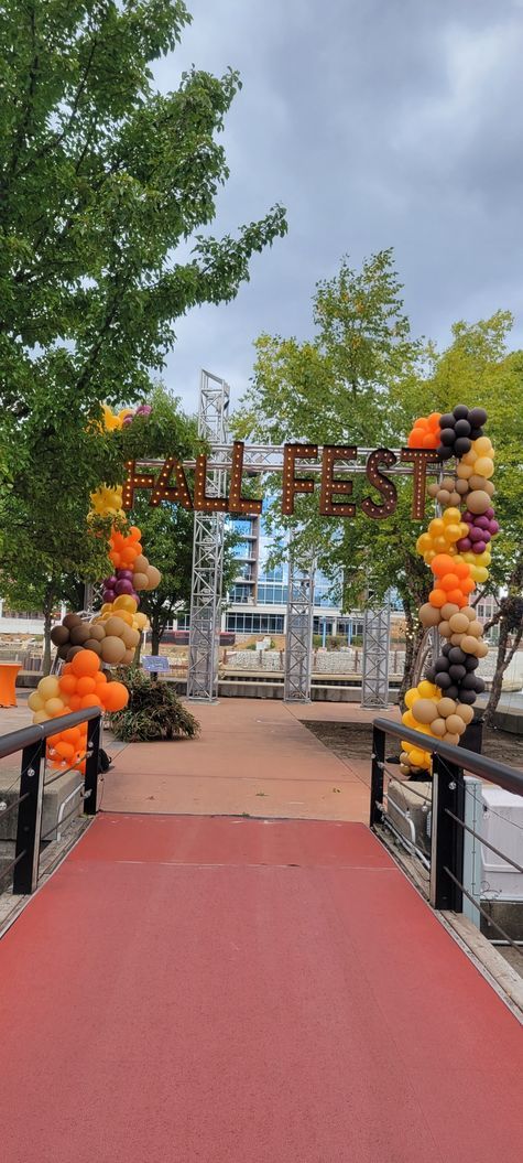 A red carpet is leading to a gate decorated with pumpkins and balloons. Fall Fest organic arch