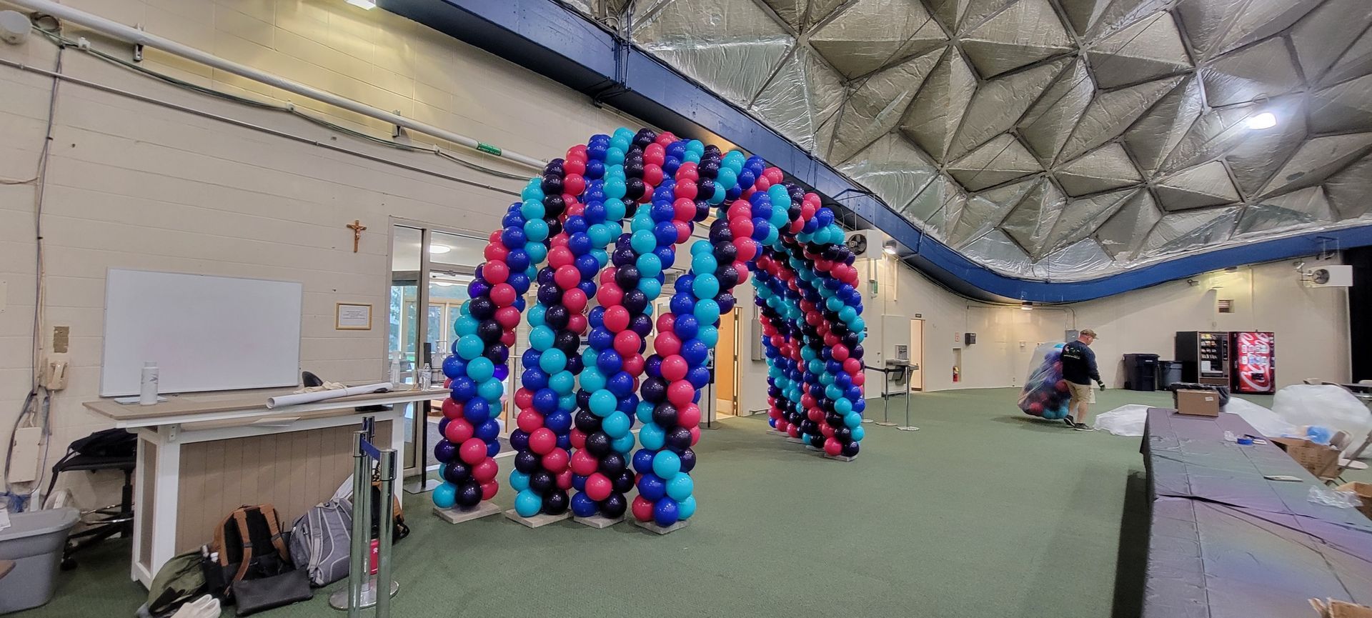 A large arch made of balloons is being built in a room.