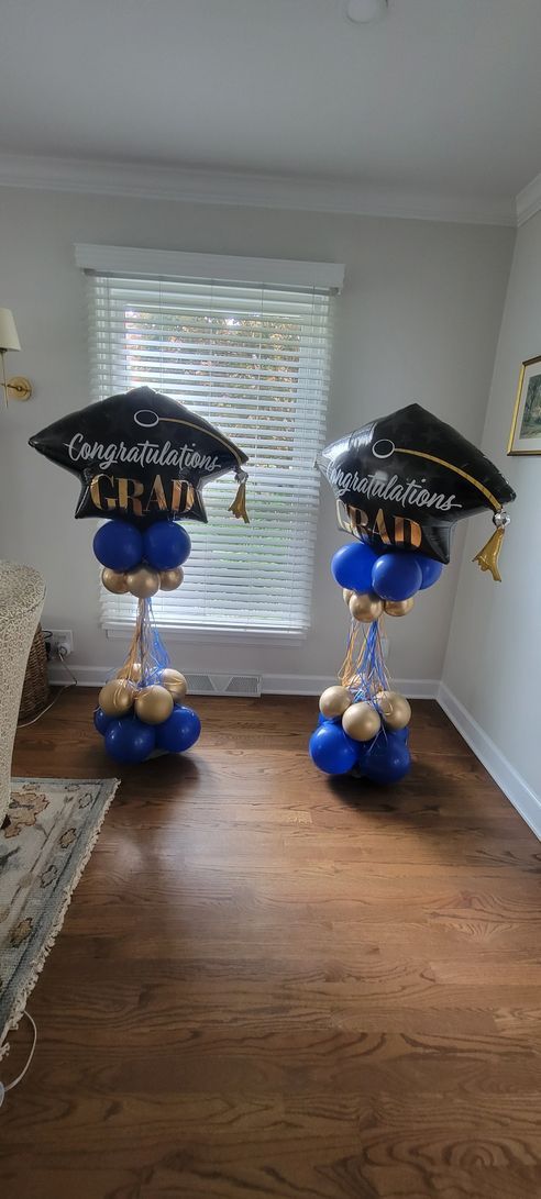 Two graduation caps are sitting on top of balloons in a living room.