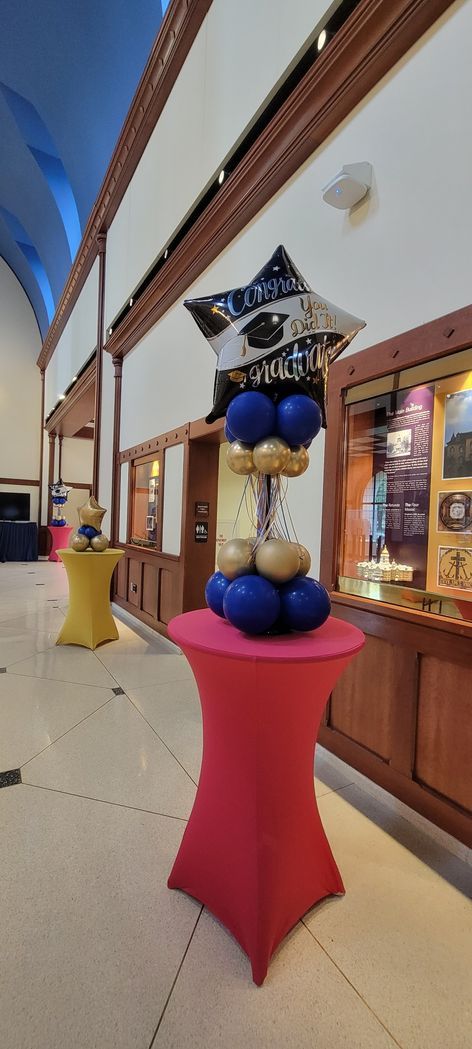 A balloon display is sitting on top of a red table in a hallway.