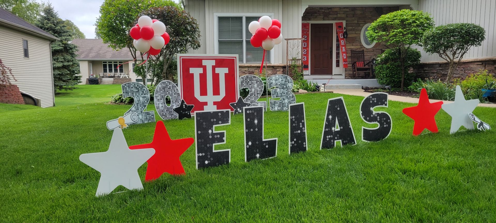 A yard sign for elias is sitting in the grass in front of a house. Indiana University