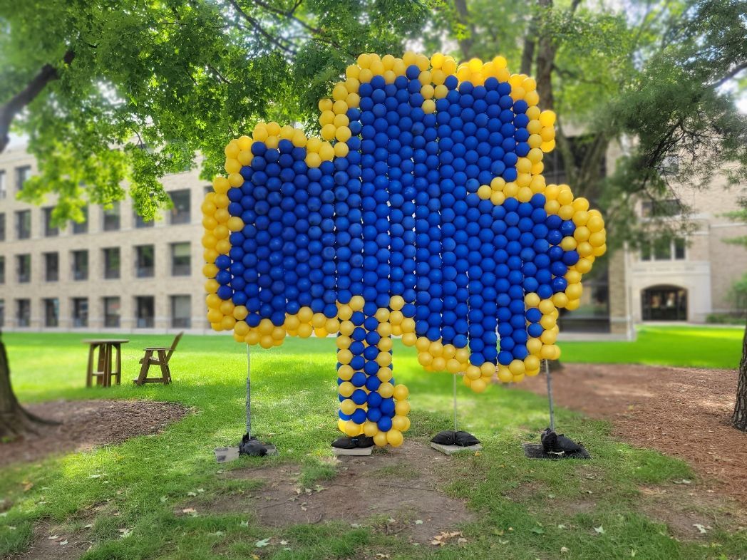 a clover made out of blue and yellow balloons in a park