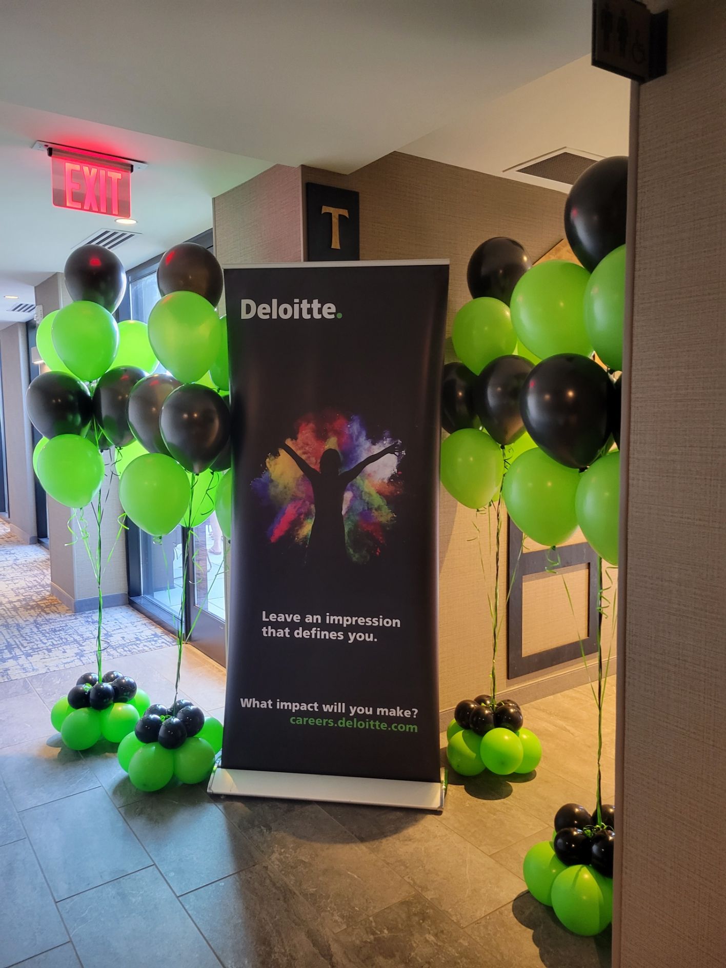 Deloitte banner flanked by black and green balloons, set in a hallway.