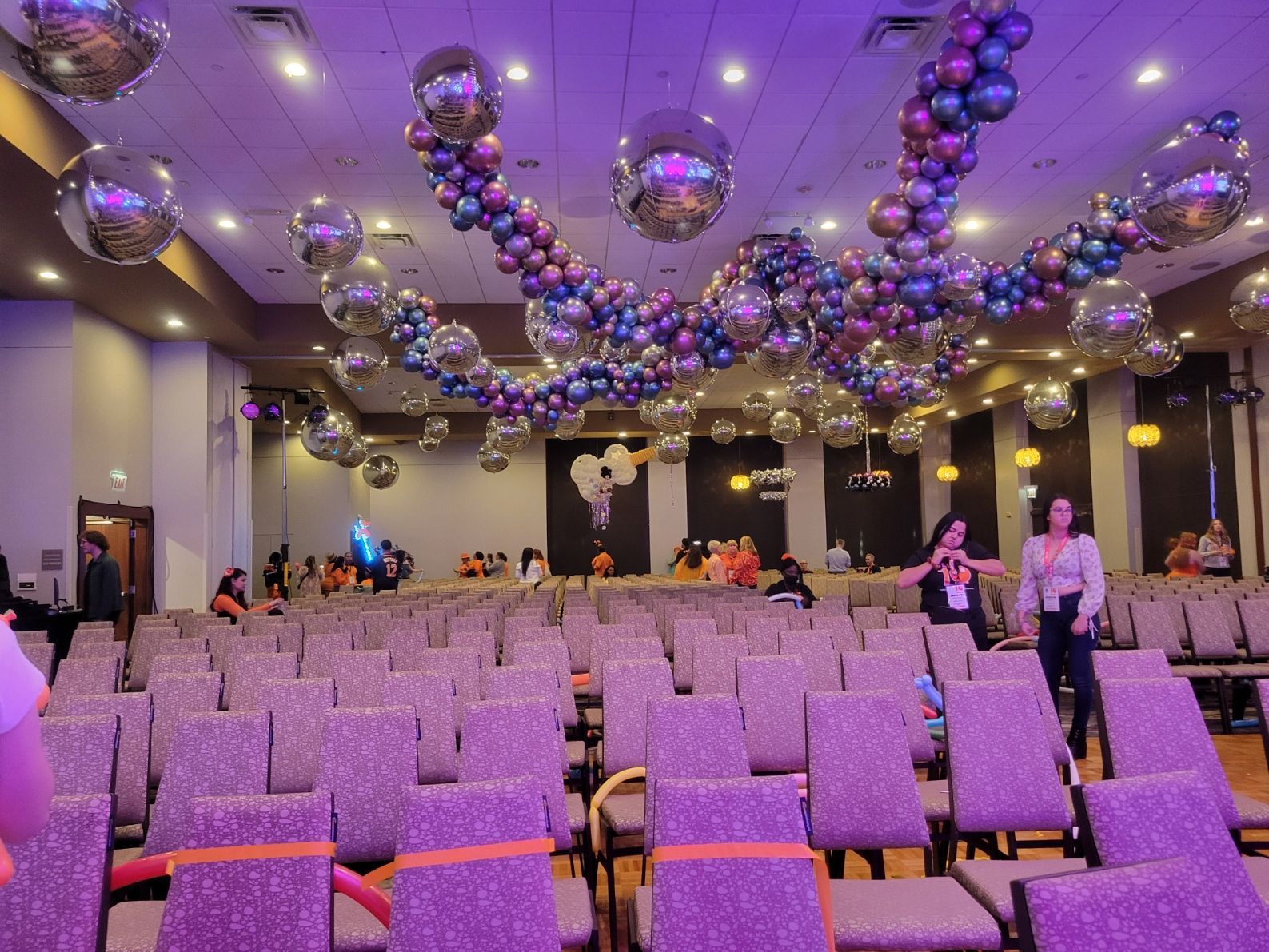A large room filled with chairs and balloons hanging from the ceiling.