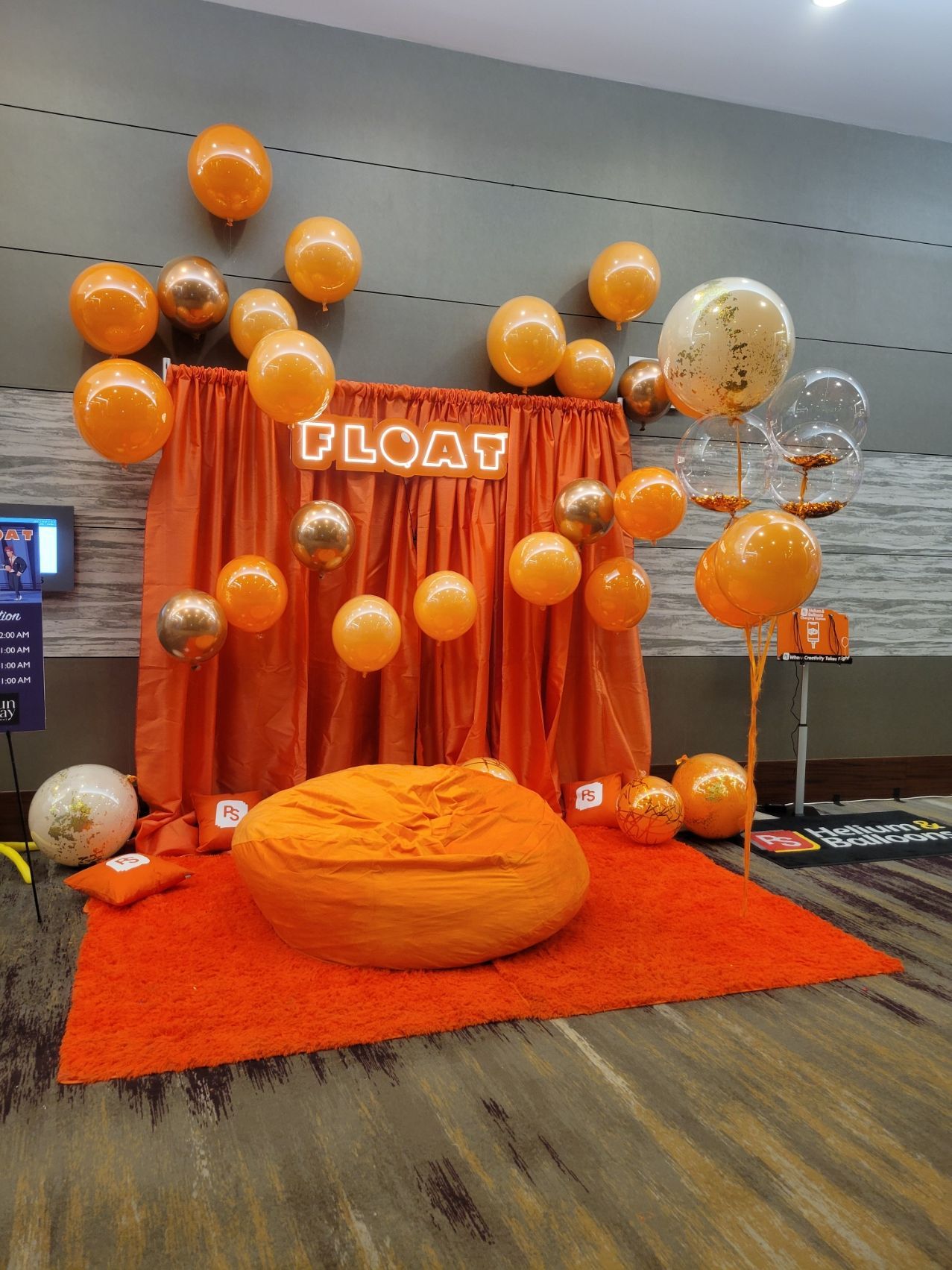 A room decorated in orange and gold with balloons and a bean bag chair.