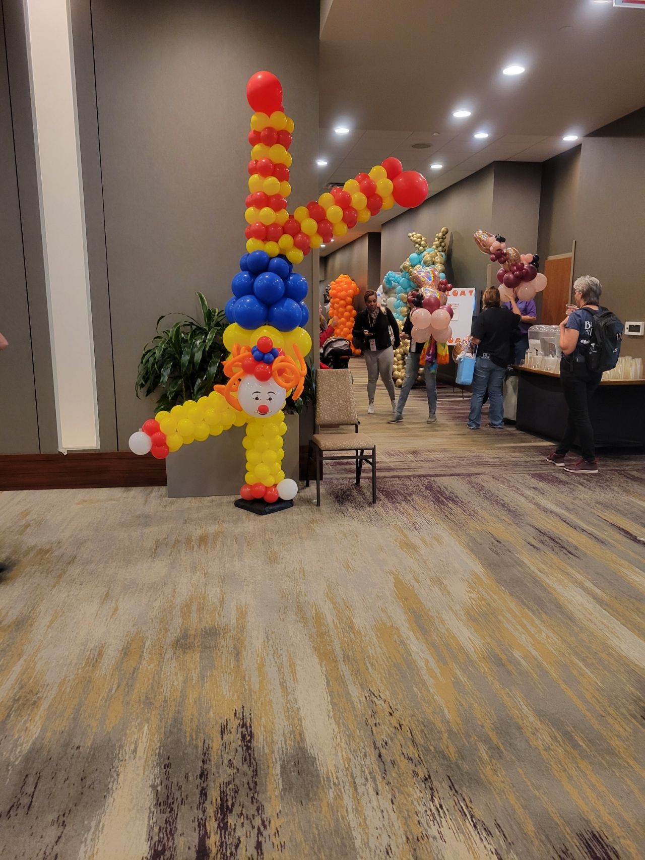 A clown made out of balloons is standing in a hallway.