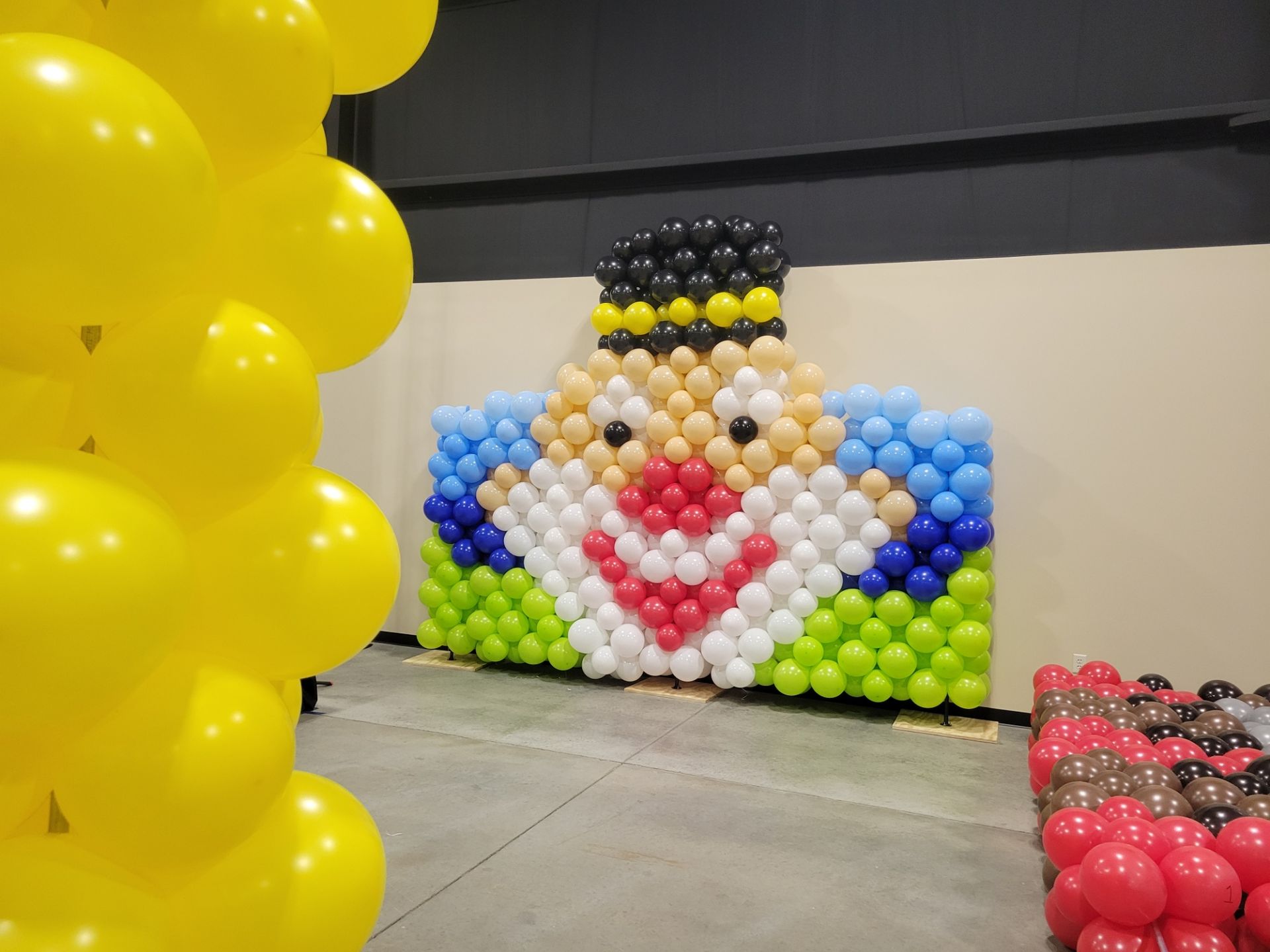 A wall made of balloons with a clown face on it