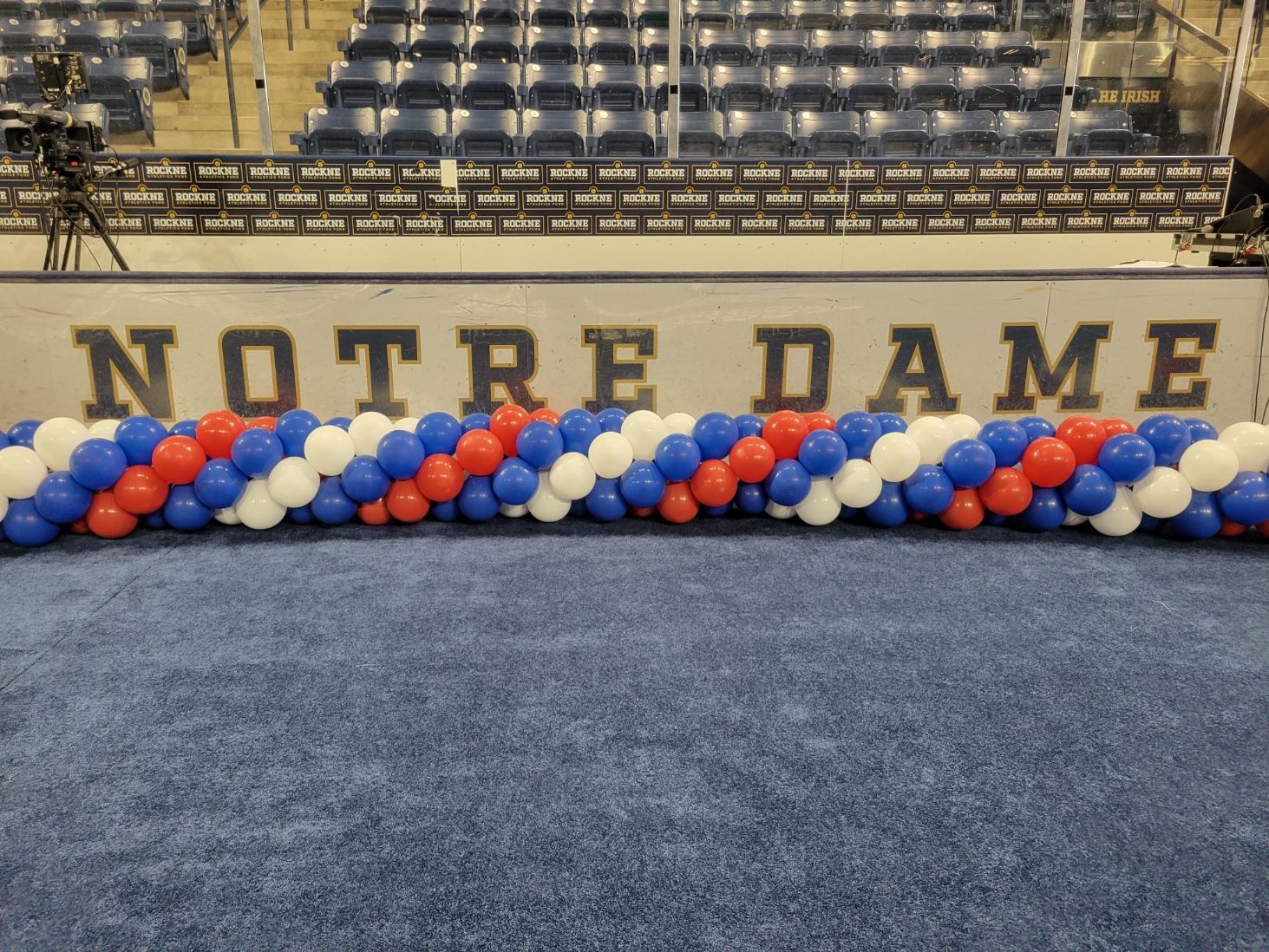 A row of red white and blue balloons in front of a sign that says notre dame