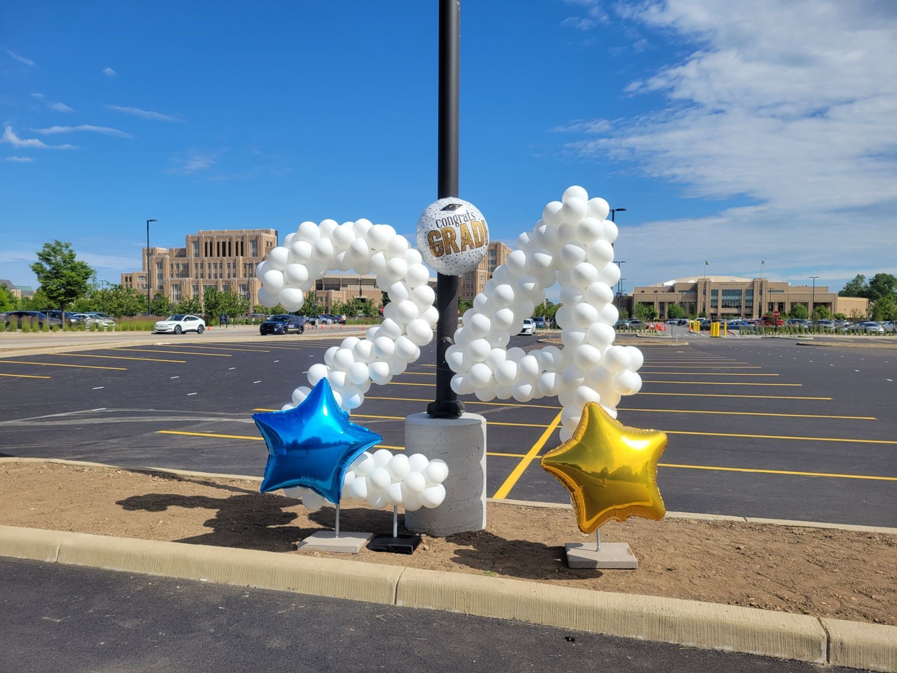 A sign made of balloons in the shape of the number 21 is in a parking lot.
