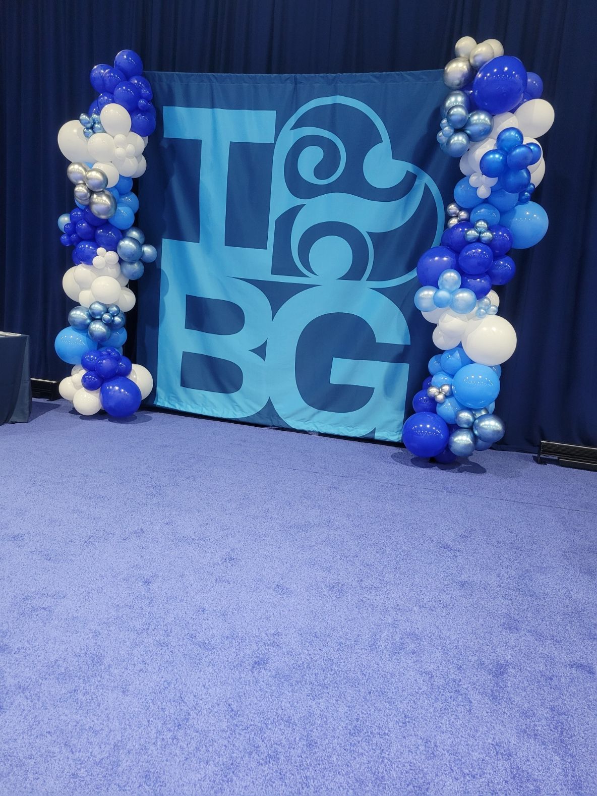 A blue banner with the word bg on it is surrounded by blue and white balloons