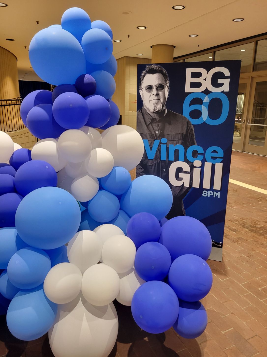 A sign for vince gill is surrounded by blue and white balloons from Fun By The yard