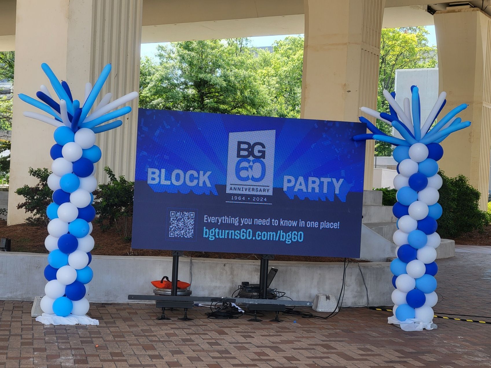 A sign that says block party is surrounded by blue and white balloons