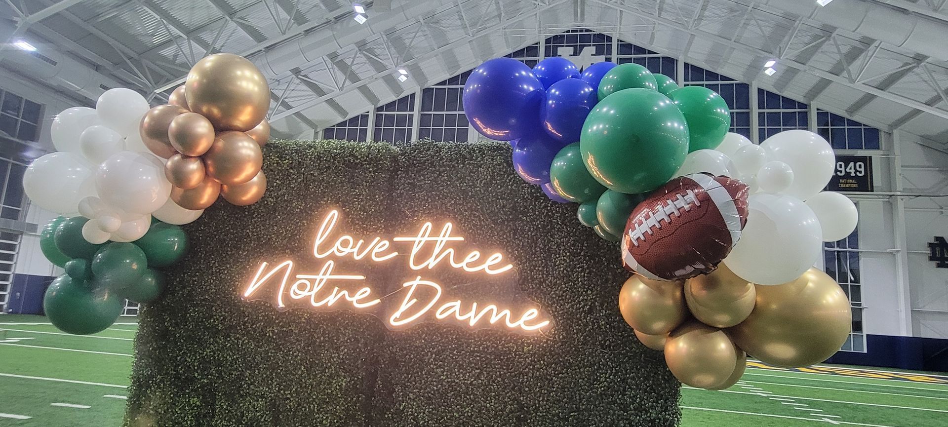 A neon sign that says `` love thee notre dame '' is surrounded by balloons.