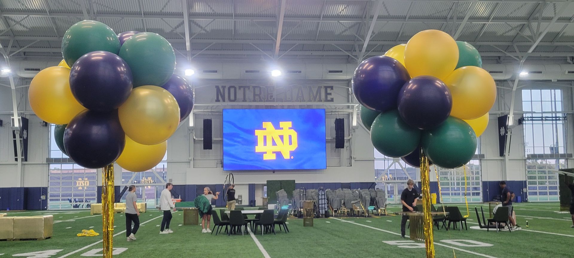 A bunch of balloons are sitting on top of a football field.