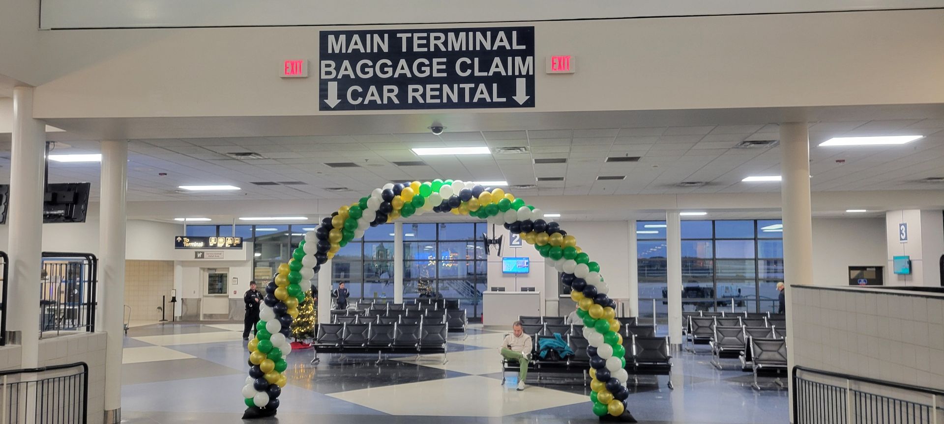 A large room with balloons and a sign that says main terminal baggage claim car rental. South Bend International Airport