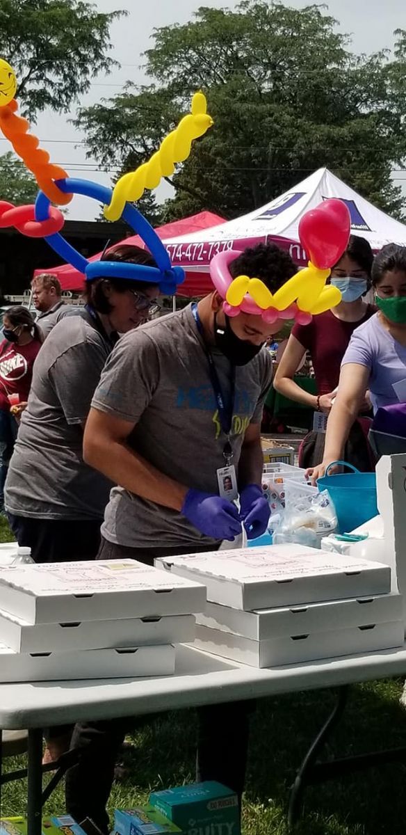A group of people are standing around a table with balloons on their heads.
