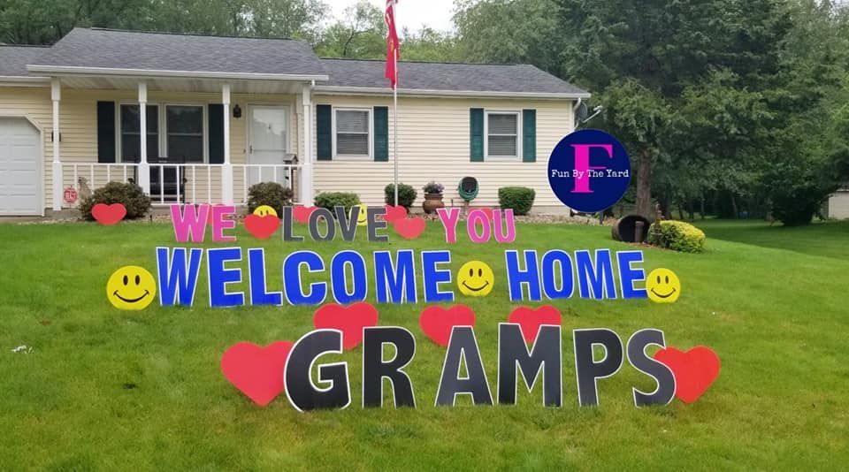 A welcome home sign for grandparents is in front of a house.