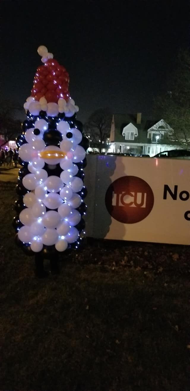 A snowman made out of balloons with a santa hat on