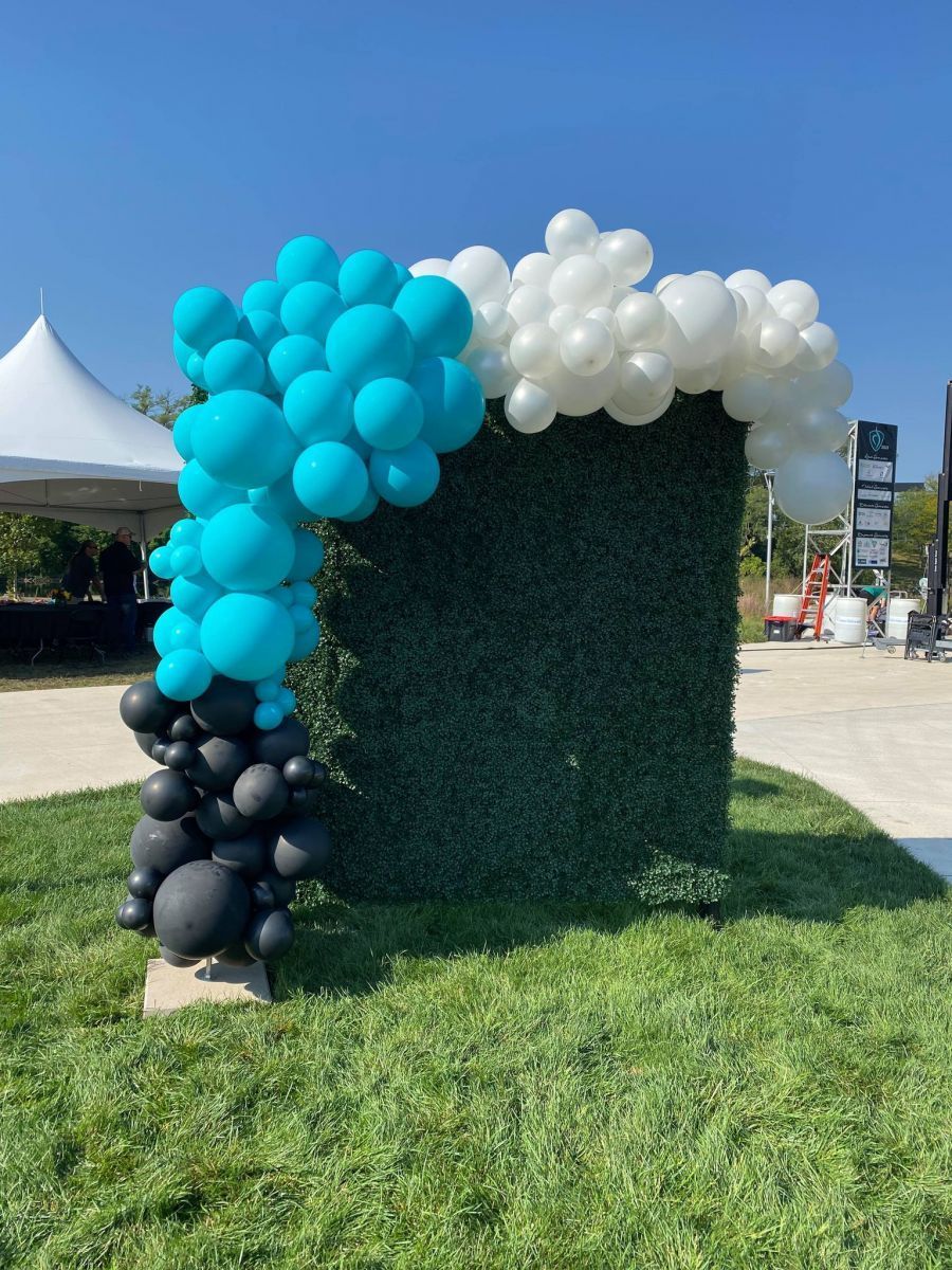 A bunch of blue and white balloons are sitting on top of a green wall.