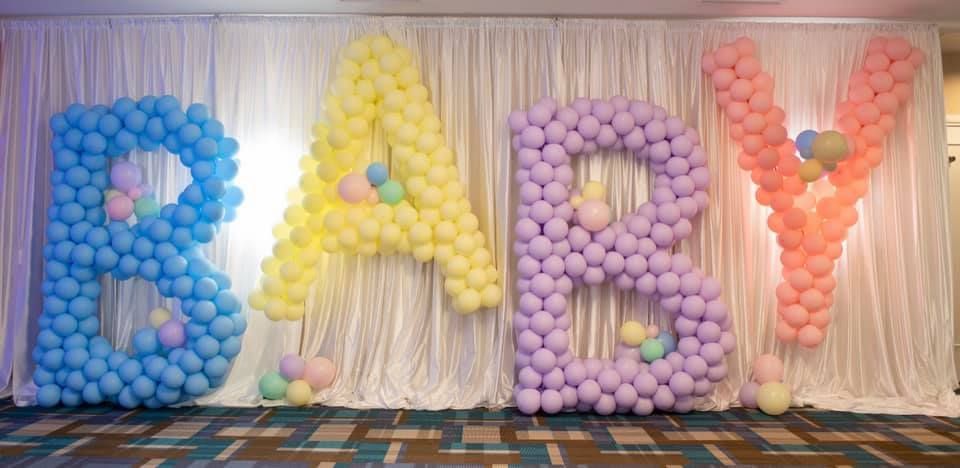 The word baby is made out of balloons on a wall.