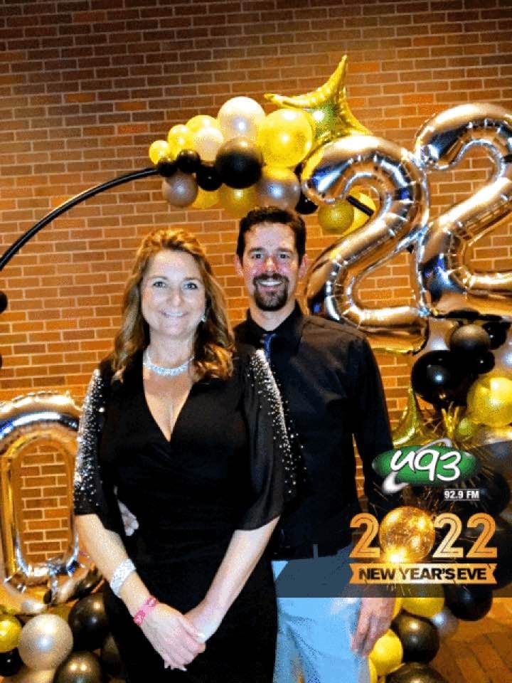 A man and a woman are posing for a picture in front of balloons.