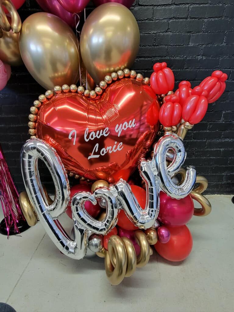 A red heart shaped balloon with the word love written on it