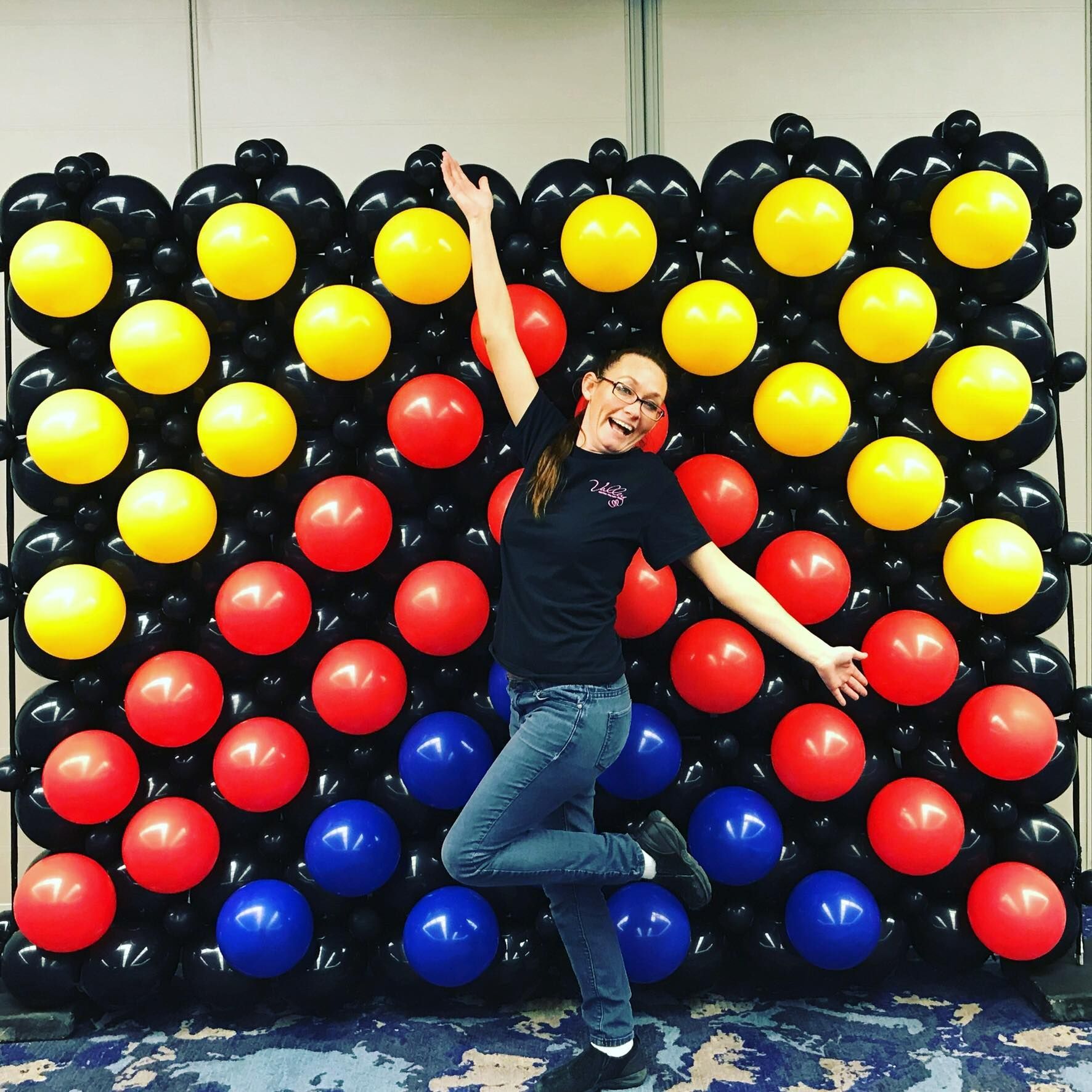 A woman is standing in front of a wall of balloons