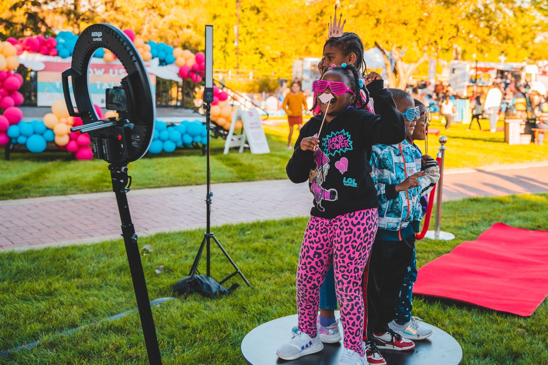 A group of children are posing for a picture in front of a ring light.