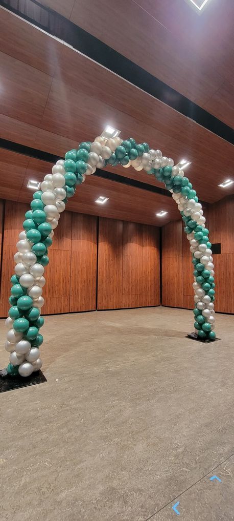 Balloon archway, green and white balloons, inside a room with wooden walls.