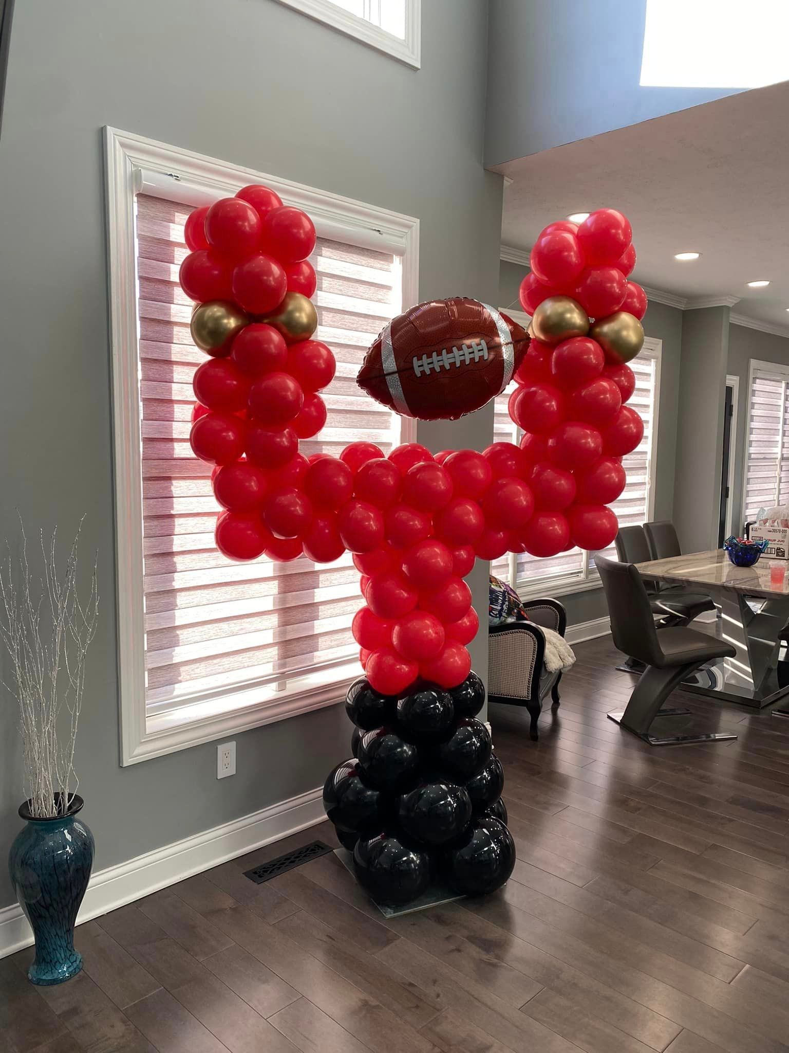 A football made out of red and black balloons in a living room.