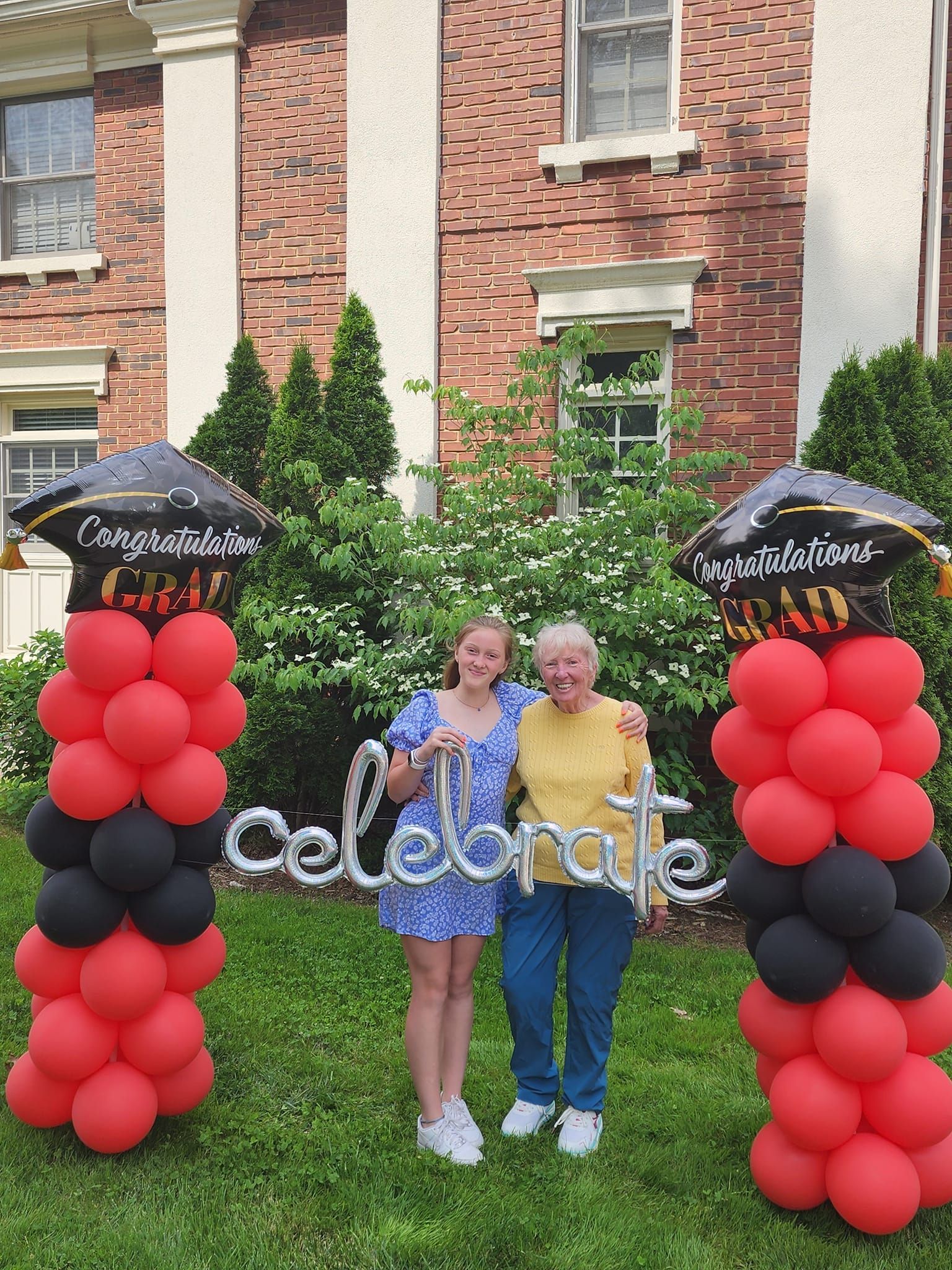 A girl and an older woman are standing in front of a sign that says celebrate.
