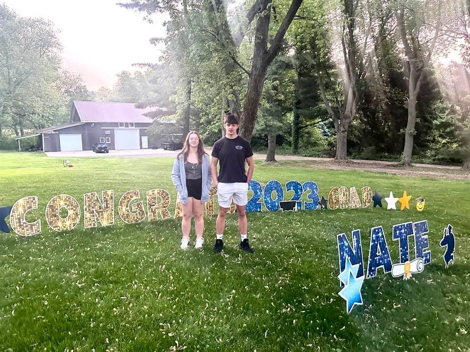 A man and a woman are standing in front of a congratulations sign.