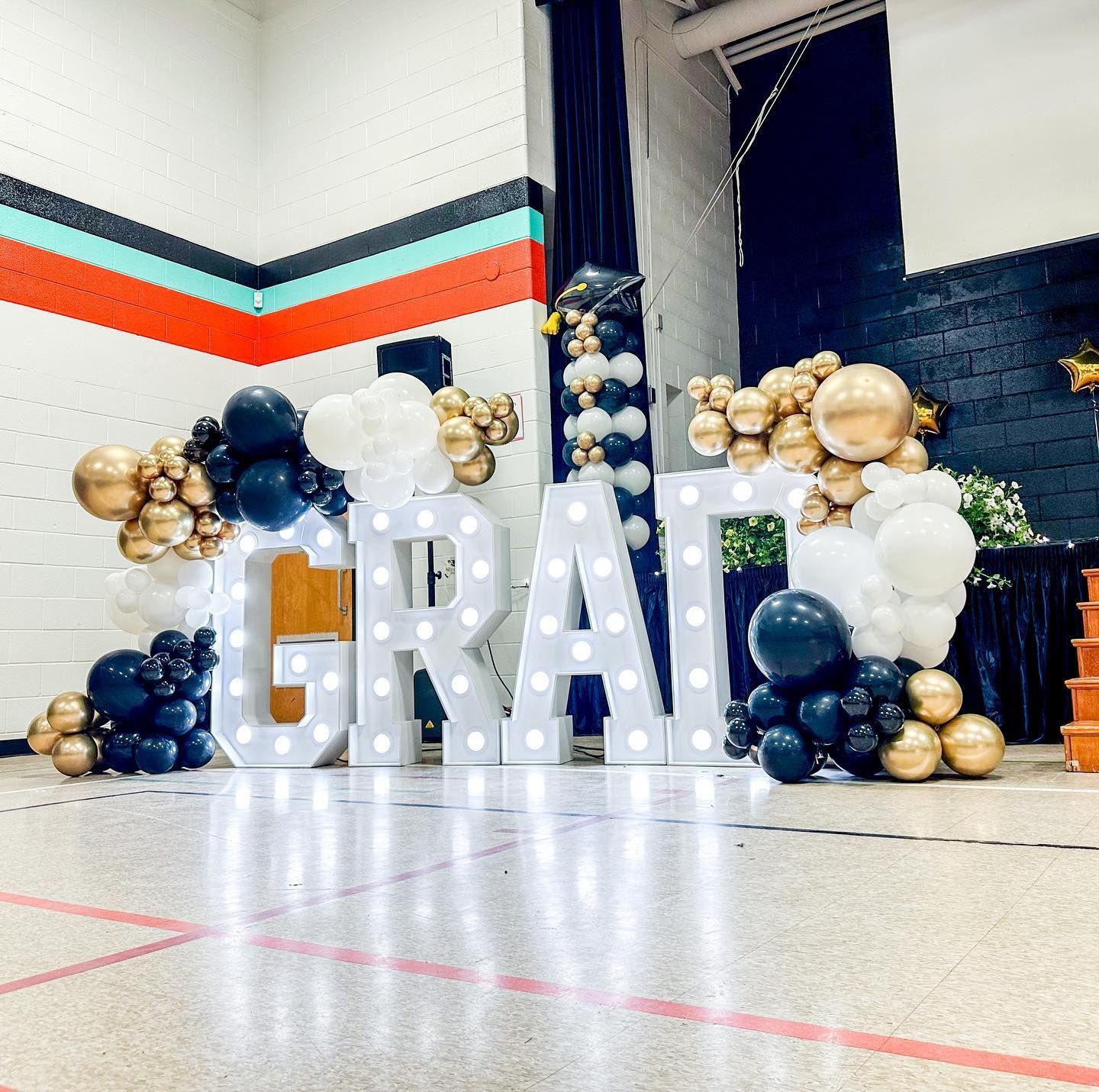 A large white sign that says ' grat ' is surrounded by balloons.