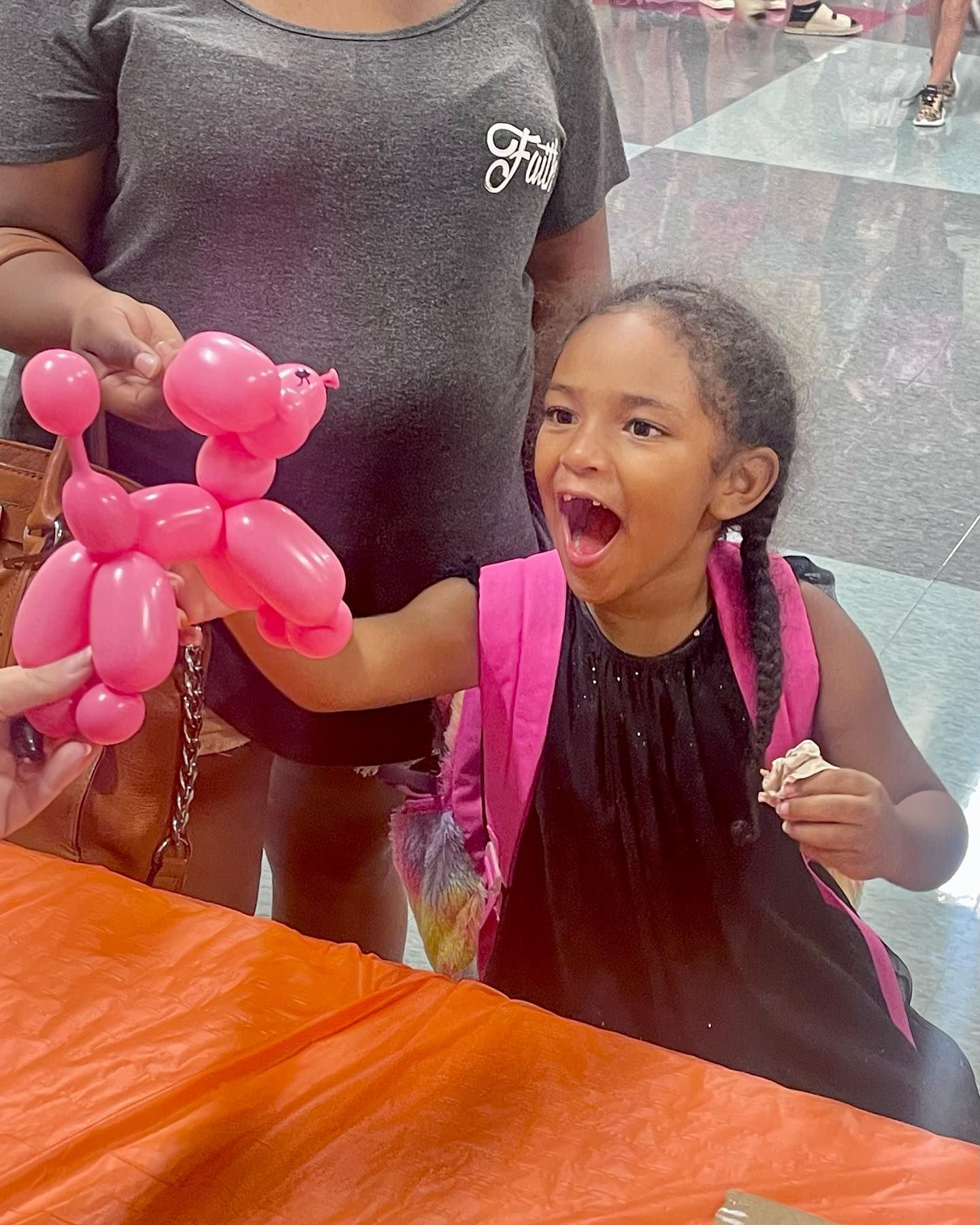 a happy girl receiving pink balloon poodle