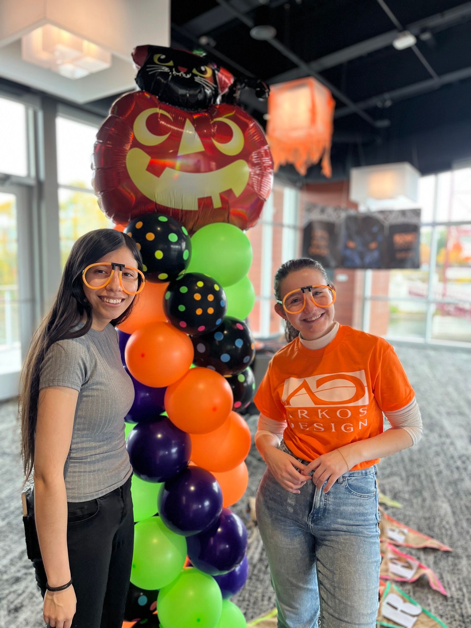 Two women are standing next to each other in front of a balloon display.