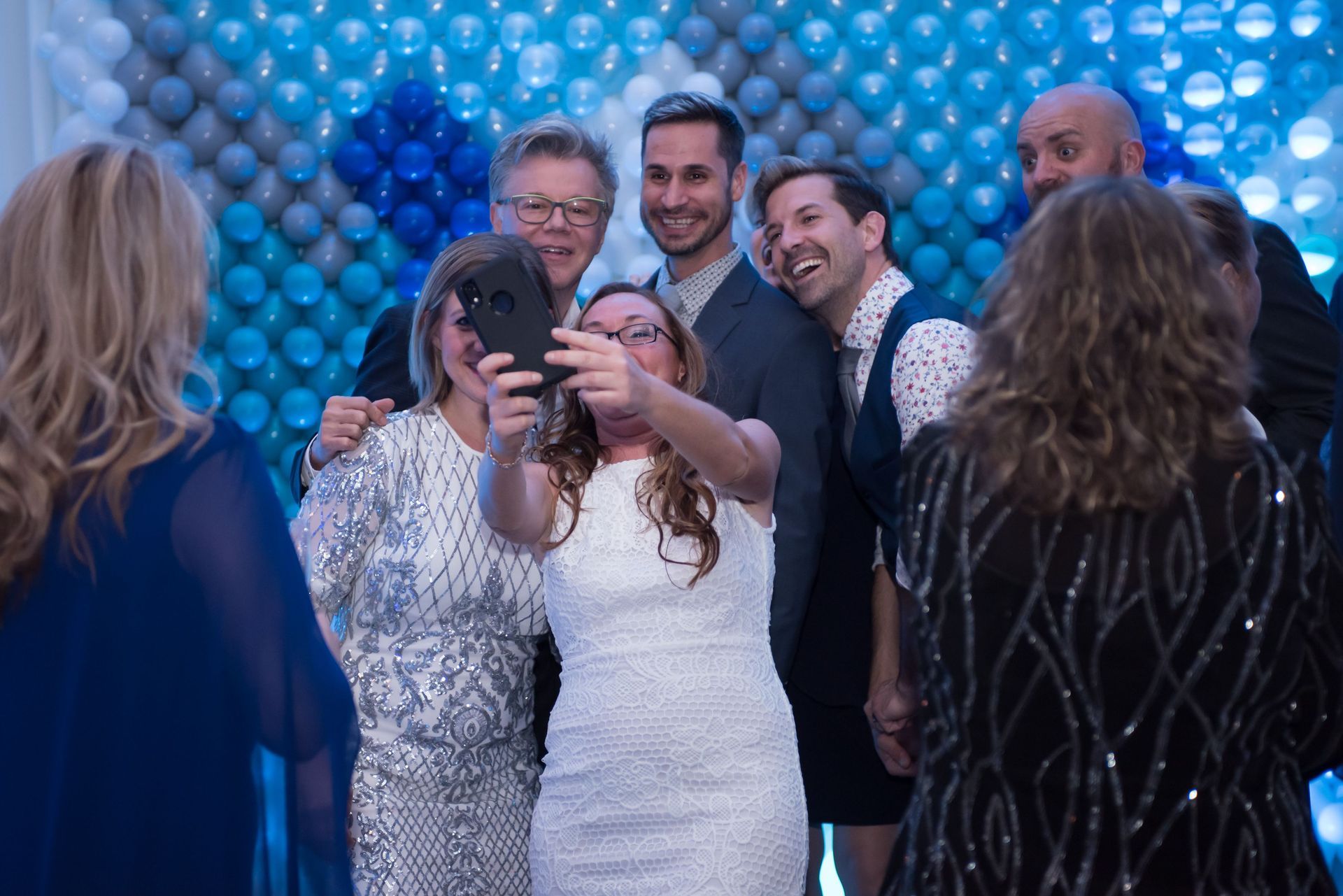 A group of people are posing for a picture in front of a wall of balloons.