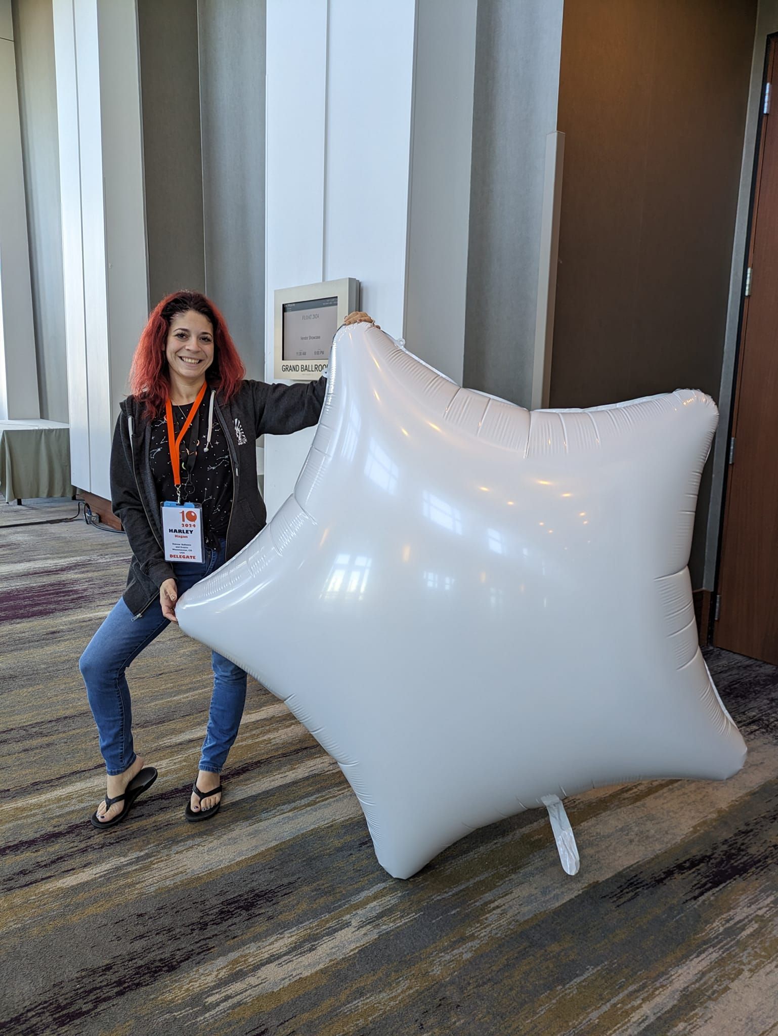 A woman is standing next to a large white balloon.