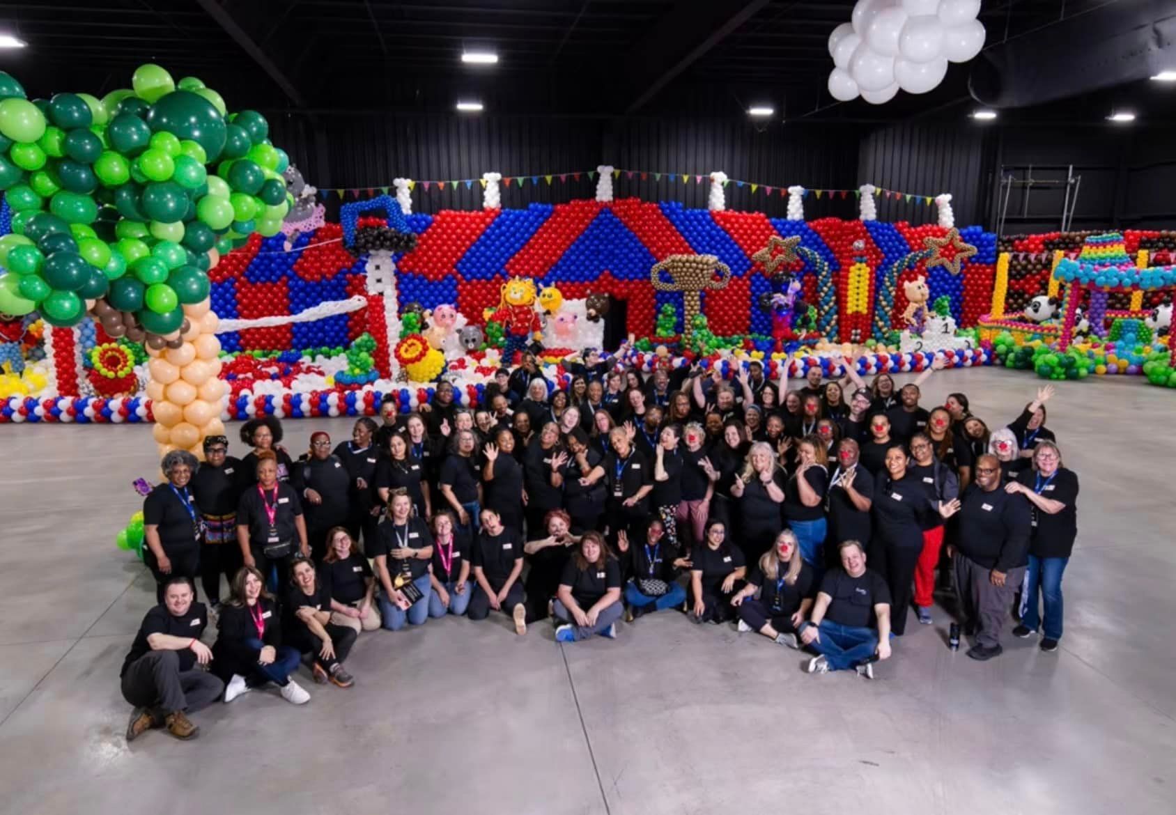 A large group of people are posing for a picture in front of balloons.