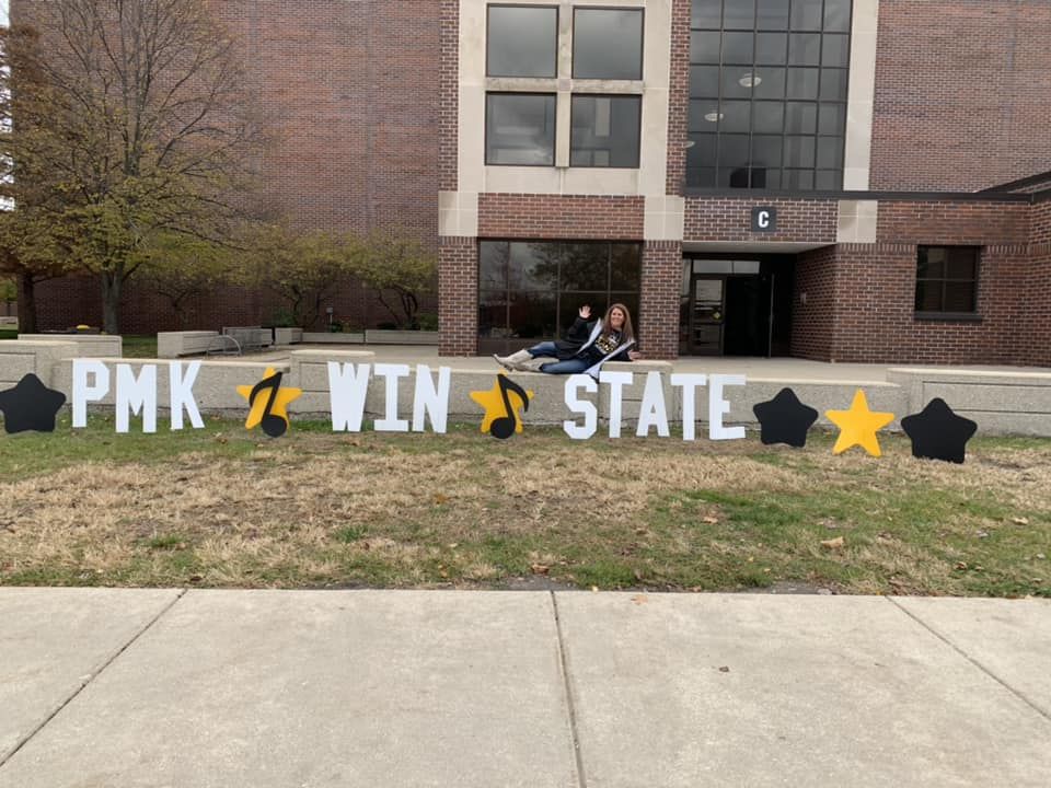 PMK wins state: Person seated by building entrance, words on lawn.